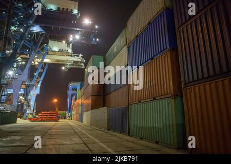 Industriehafen mit Containern. Stapel von Containern, Portalkran in der Nacht. Industrial Container Yard für Logistik Import Export Geschäft Stockfoto