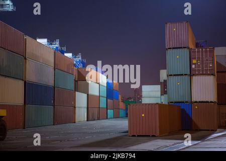 Industriehafen mit Containern. Stapel von Containern, Portalkran in der Nacht. Industrial Container Yard für Logistik Import Export Geschäft Stockfoto