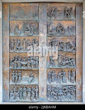 MONOPOLI, ITALIEN - 6. MÄRZ 2022: Die Bronzereliefs am Tor der Kirche Chiesa di Sacro Cuore von Wolfgang Stempfele aus dem Jahr 2002. Stockfoto