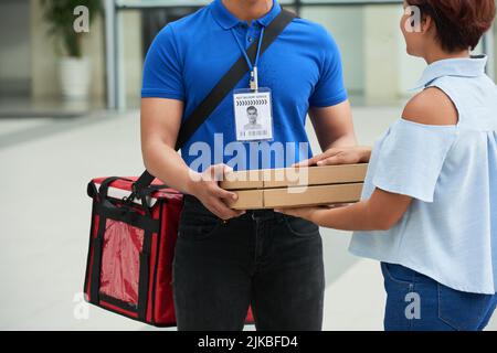 Zugeschnittenes Bild des Lieferers, der der Frau Pizzaboxen gab Stockfoto