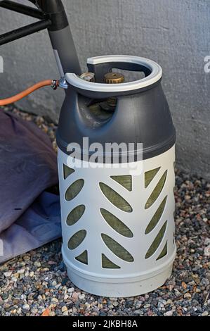 treibgasflasche, die auf Kies im Garten steht Stockfoto