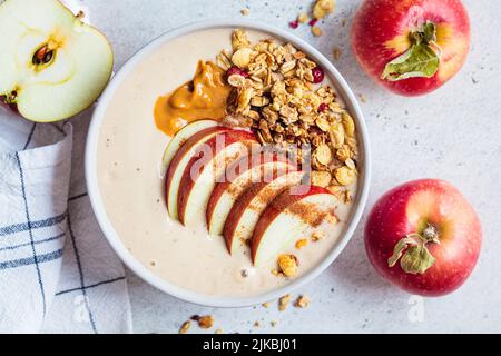 Apfelkuchen-Smoothie-Schüssel mit Müsli und Erdnussbutter, Draufsicht, Nahaufnahme. Herbstrezept. Vegane Küche. Stockfoto