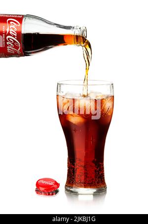 Chisinau, Moldawien - 31. Juli 2022: Cola aus der Flasche mit Spritzwasser in das Glas gießen. Klassische Flasche Coca-Cola isoliert auf weißem Hintergrund Stockfoto
