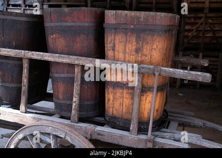 Alte Holzweinfässer auf einem Holzkarren in der französischen Stadt Ribeauvillé im Elsass Stockfoto