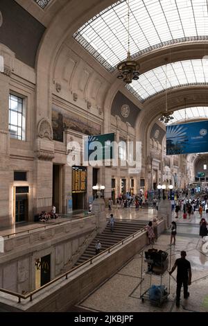 Ankunftshalle des Mailänder Hauptbahnhofs oder Milano Centrale. Werbetafeln und Passagiere im Gebäude Stockfoto