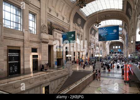 Ankunftshalle des Mailänder Hauptbahnhofs oder Milano Centrale. Werbetafeln und Passagiere im Gebäude Stockfoto