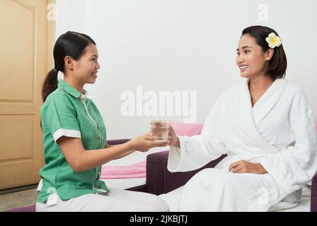Spa Salon Administrator bietet ein Glas frisches Wasser für den Kunden Stockfoto