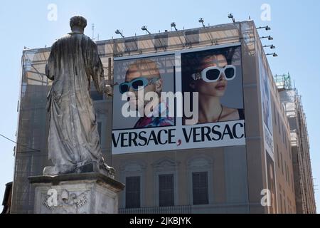 Statue des Apostels Saint Paul auf der Ponte Sant'Angelo in Rom mit Blick auf ein modernes Gebäude, das mit einer Plakatwand des Modeunternehmens Versace renoviert werden soll Stockfoto