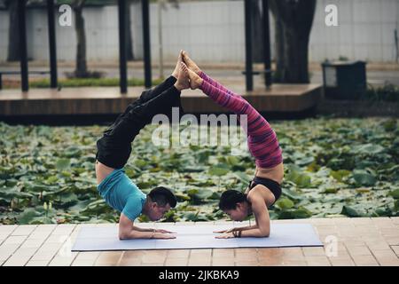 Junges asiatisches Paar, das schwierige acroyoga-Übung durchführt Stockfoto