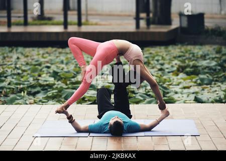 Junges asiatisches Paar, das acroyoga praktiziert Stockfoto