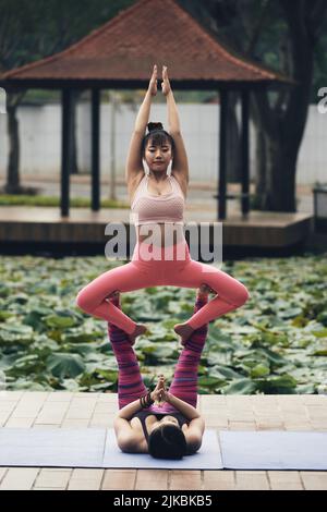 Junge vietnamesische Frauen, die schwierige acroyoga-Pose durchführen Stockfoto