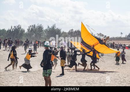 Denpasar, Indonesien. 31.. Juli 2022. Die Teilnehmer fangen ihren Drachen während der Landung. Tausende von Menschen strömen nach Mertasari Beach in Sanur, um während der Kitesaison auf Bali, die jedes Jahr von Mai bis September stattfindet, zwischen der Trockenzeit ein Drachenfest zu veranstalten. Das Festival markiert die beste Zeit des Jahres, um Bali zu besuchen. Die Farben Rot, Weiß, Schwarz und Gelbgold repräsentieren die Inkarnationen balinesischer Hindu-Gottheiten. (Foto von Dicky Bisinglasi/SOPA Images/Sipa USA) Quelle: SIPA USA/Alamy Live News Stockfoto