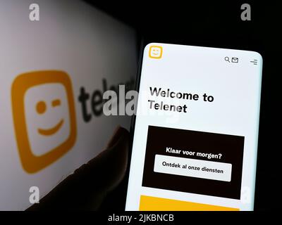 Person, die Mobiltelefon mit der Webseite des belgischen Unternehmens Telenet Group Holding N.V. auf dem Bildschirm vor dem Logo hält. Konzentrieren Sie sich auf die Mitte des Telefondisplays. Stockfoto