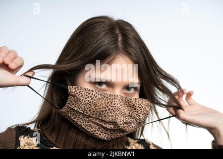 Frau, die Spaß mit einer Maske trägt braune Maske, schützt sich vor covid Stockfoto