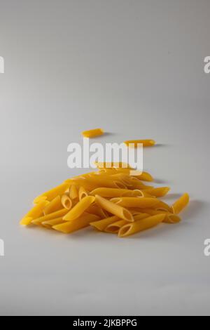 Penne rigate italienische Pasta frei auf weißem Hintergrund gestreut Stockfoto