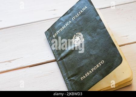 Uralter italienischer Reisepass auf einem weißen Tisch im Hintergrund. Horizontale Ansicht. Stockfoto