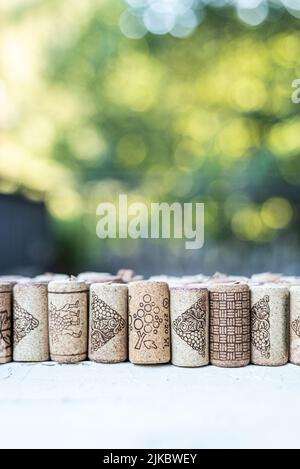 Vertikale Reihe von Korken, auf einem weißen Holztisch und mit einem natürlichen grünen Hintergrund. Grüner negativer Bereich außerhalb des Fokus. Konzept der Natur im Freien. Version Stockfoto