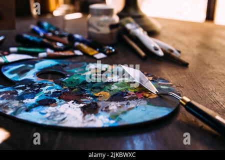 Palette in Farbe und ein Palettenmesser auf einem Holztisch. Stockfoto