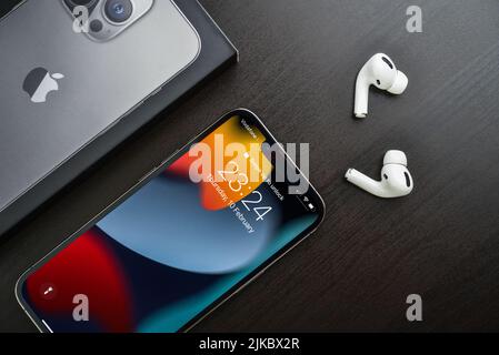 KIEW, UKRAINE - 10. FEBRUAR 2022: Ausgepacktes neues Apple iPhone 13 Pro Space Grey mit AirPods Pro Kopfhörern auf schwarzem Hintergrund. Stockfoto