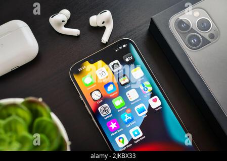 KIEW, UKRAINE - 10. FEBRUAR 2022: Ausgepacktes neues Apple iPhone 13 Pro Space Grey mit AirPods Pro Kopfhörern auf schwarzem Hintergrund. Stockfoto