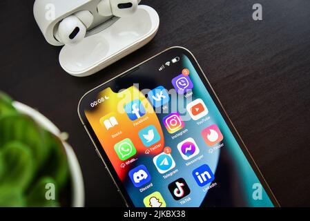 KIEW, UKRAINE - 10. FEBRUAR 2022: Social-Media-Symbole auf dem Bildschirm des iPhone 13 Pro mit AirPods Pro Kopfhörern. Social Media sind das beliebteste Tool für Stockfoto
