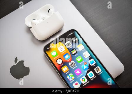KIEW, UKRAINE - 10. FEBRUAR 2022: Apple-Produkt. MacBook Pro, iPhone 13 Pro mit AirPods Pro Kopfhörern auf schwarzem Hintergrund Draufsicht. Technologie-ga Stockfoto