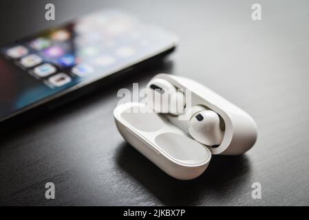 KIEW, UKRAINE - 10. FEBRUAR 2022: Ausgepackte neue AirPods Pro Kopfhörer mit Apple iPhone 13 Pro Space Grey auf schwarzem Hintergrund. Stockfoto