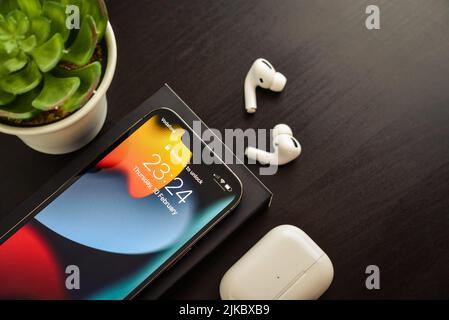 KIEW, UKRAINE - 10. FEBRUAR 2022: Ausgepacktes neues Apple iPhone 13 Pro Space Grey mit AirPods Pro Kopfhörern auf schwarzem Hintergrund. Stockfoto