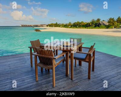 Holztisch und Stühle auf der Terrasse mit Blick auf den Strand und das Meer Stockfoto