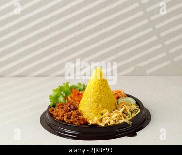 Kleiner Kegelförmiger Gelber Reis Oder Tumpeng Mini Nasi Kuning. Indonesisches Festessen für Indoneia Unabhängigkeitstag 17 Agustus Stockfoto