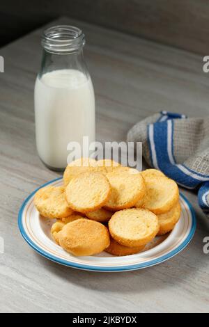 Roti Bagelen, getrocknetes Brot mit Sugar Sprinkle, serviert auf Holztisch, serviert mit Milch Stockfoto