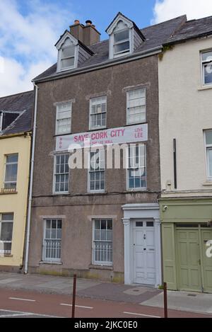 Haus am Ufer des Flusses Lee, Cork City, Irland mit einem Banner gegen das geplante Hochwasserwandprojekt für 15km von Hochwasserbarrieren entlang des Flussufers Stockfoto