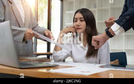 Junge asiatische Frau, die mit übermäßiger Arbeit unzufrieden ist Stockfoto