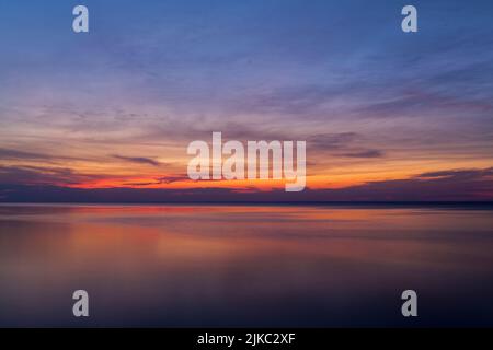 Dramatischer Himmel während des farbenfrohen roten und violetten Sonnenuntergangs über dem Ozean am äußeren Ufer von Long Island New York Stockfoto