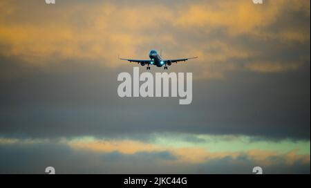Die Silhouette eines Passagierflugzeugs, das vor dem Hintergrund des Sonnenuntergangs landet. Stockfoto