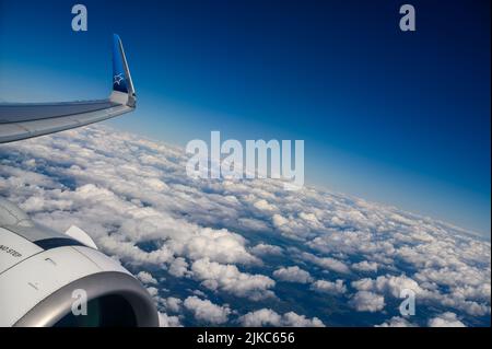 Über den Wolken: Die Flügelspitze und der Düsentoolmotor eines Air Transat Airbus A321, der über weißen Cumuluswolken über der Südküste Englands fliegt. Stockfoto