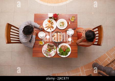 Direkt über dem Blick auf das liebende junge Paar, das eine bedeutsame Veranstaltung in einem luxuriösen Restaurant feiert, während es ein romantisches Date hat Stockfoto