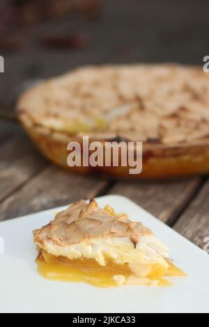 Zitrone Meringue Pie auf grauem Holzhintergrund in Glas Pie Pfanne Stockfoto