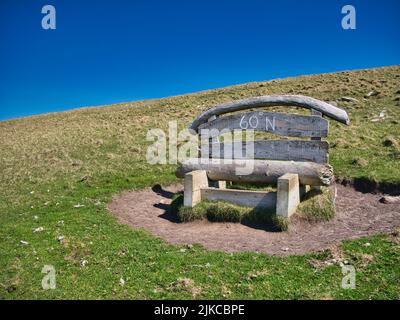 Eine Holzbank auf der Insel Mousa, Shetland, Großbritannien, markiert die Position der 60 Grad Nordparallel, die durch die Inseln verläuft. Stockfoto