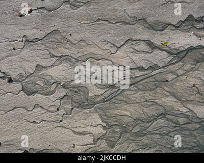 Bei Ebbe an einem feinen Sandstrand Wasserfächeln. Stockfoto