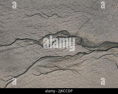 Bei Ebbe an einem feinen Sandstrand Wasserfächeln. Stockfoto