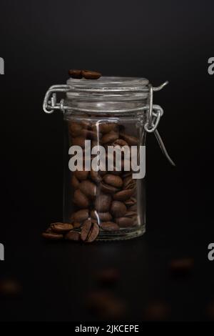 Studiofoto von braunen Kaffeebohnen in einem Glas auf schwarzem Hintergrund Stockfoto