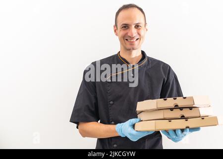 Ein Koch in Uniform bietet Ihnen eine Pizzabox an. Lächelnd auf die Kamera Stockfoto