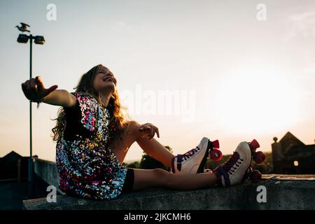 Mädchen glücklich Roller Boot und Tanz bei Sonnenuntergang Stockfoto