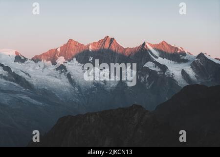 Die ersten Sonnenstrahlen des Tages treffen auf die höchsten Gipfel der Schweiz Stockfoto