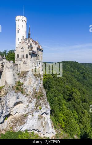 Foto von schloss lichtenstein oder Schloss auf bewaldeten Felsklippen in den Schwäbischen Alpen im Sommer. Saisonales Panorama des romantischen Märchenpalastes im gotischen Revival-Stil über dem Himmel. Berühmtes europäisches Wahrzeichen Stockfoto