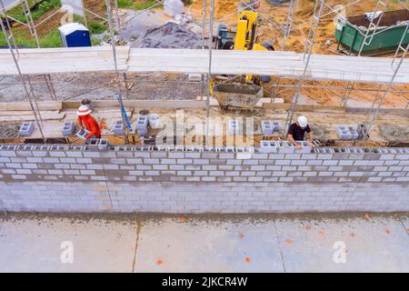 Baustellenarbeiter auf Gerüsten Mauerwerk Mauerwerk Zunder Betonblöcke zu verlegen Stockfoto