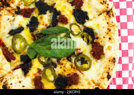 Schwarze Pfeffer-Rindfleisch-Pizza auf einem rot karierten Papier Stockfoto