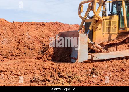 Ein Bulldozer arbeitet mit Erdboden, während er Landschaftsbau auf einer Baustelle macht Stockfoto