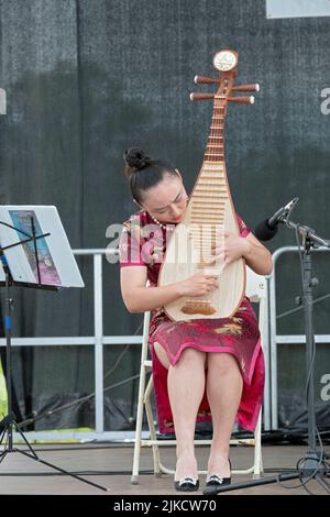 Ein schönes Mitglied des Chinese Music Ensemble of New York spielt die Pipa, ein traditionelles chinesisches Instrument. Auf dem Hong Kong Dragon Boat Fest Stockfoto